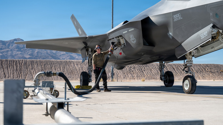 A United States Air Force ground crew member refueling an F-35 jet fighter.