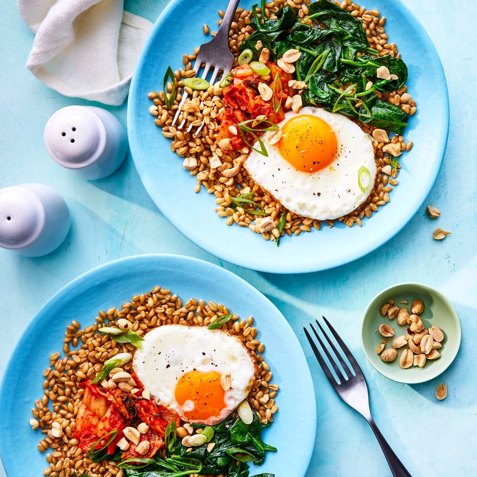 a recipe photo of the Wilted Spinach and Fried Egg Wheat Berry Bowl Credit: Photographer: Antonis Achilleos, Prop Stylist: Shell Royster, Food Stylist: Ruth Blackburn