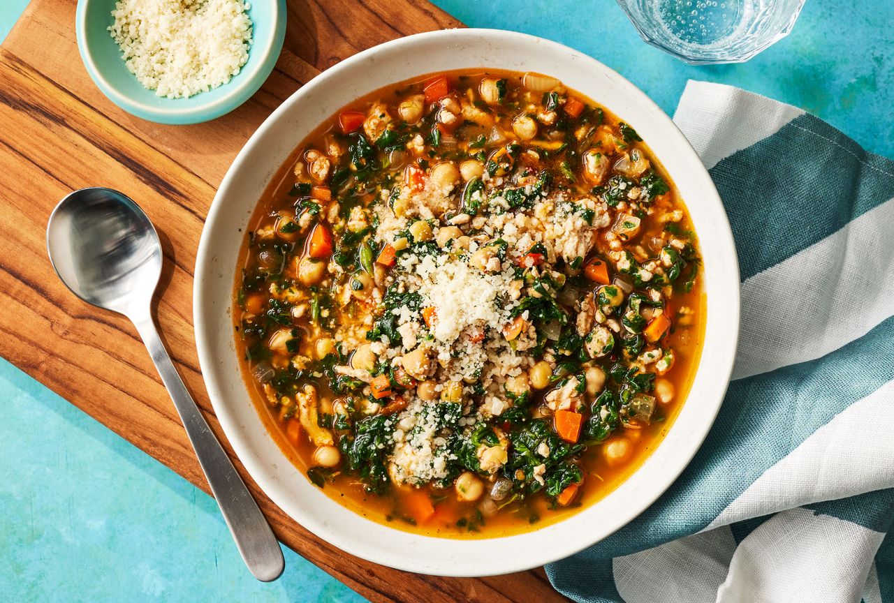 Hearty chickpea & spinach stew in a white bowl, with grated parmesan cheese sprinkled on top Credit: Photographer: Victor Protasio, Food Stylist: Margaret Dickey, Prop Stylist: Claire Spollen