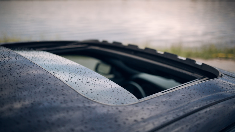 Close-up view of open car sunroof with water droplets on it.