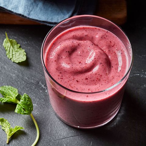 pink smoothie made with mint and kefir in glass on black background