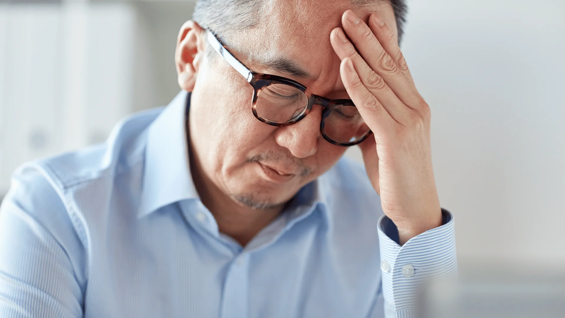 exhausted man with a headache holding his temples