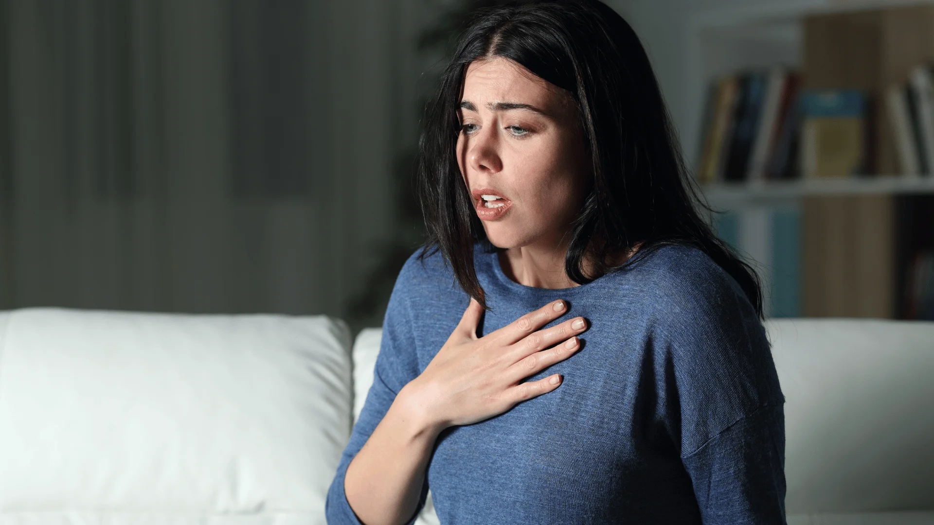 woman having anxiety attack holding her chest at home