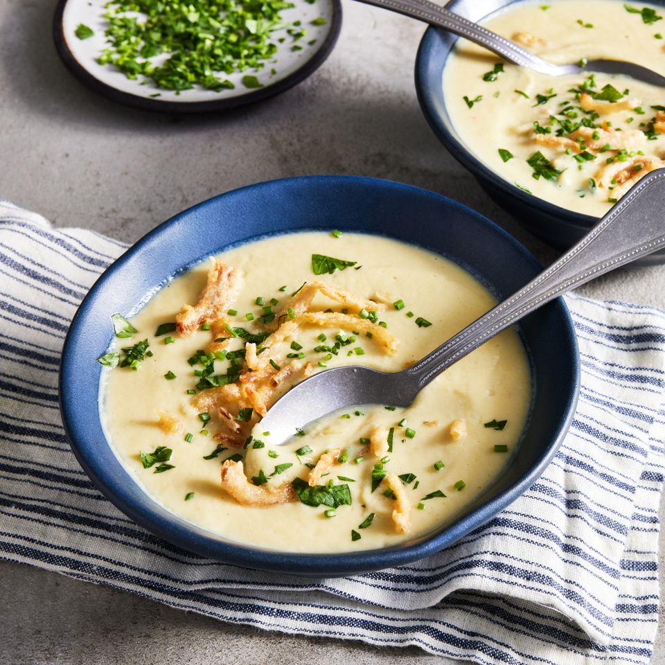 a recipe photo of the Creamy Cauliflower & Zucchini Soup served in a bowl with a spoon in it and a towel under it Credit: Photographer: Jennifer Causey, Food stylist: Ali Ramee, Prop stylist: Clairen Spollen
