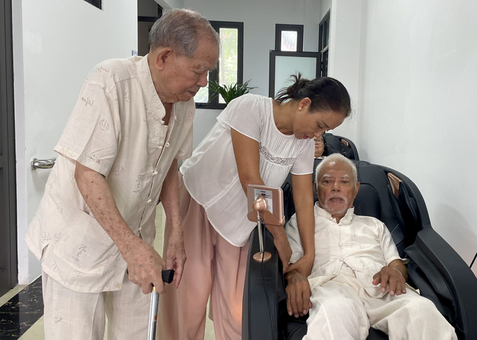 Ms. Mai Huong supported her father using a massage machine at the Tay Ho Ward Elderly Care Facility on October 1. Photo: Phan Duong