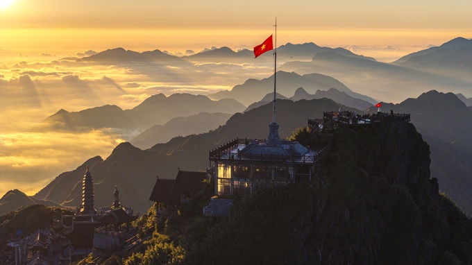 The Vietnamese national flag rises above Fansipans spiritual complex as clouds cover the surrounding mountains at sunrise. Photo courtesy of Sun World